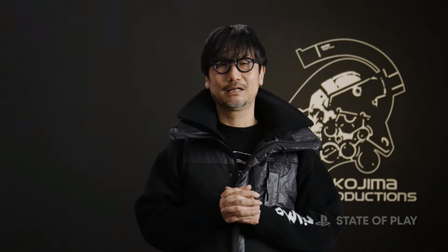 Hideo Kojima, Kojima Productions logosunun önünde duruyor,